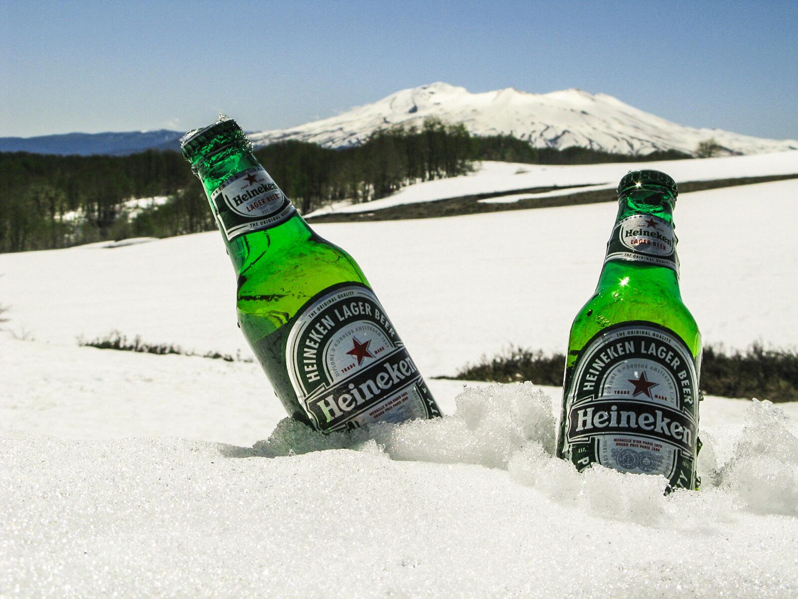 Free photo Two bottles of Heineken beer chilled in the snow