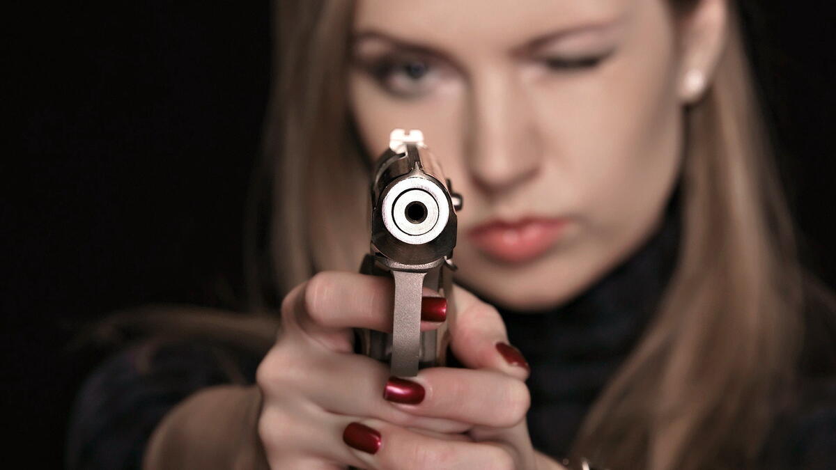Девушка целиться из блестящего пистолета