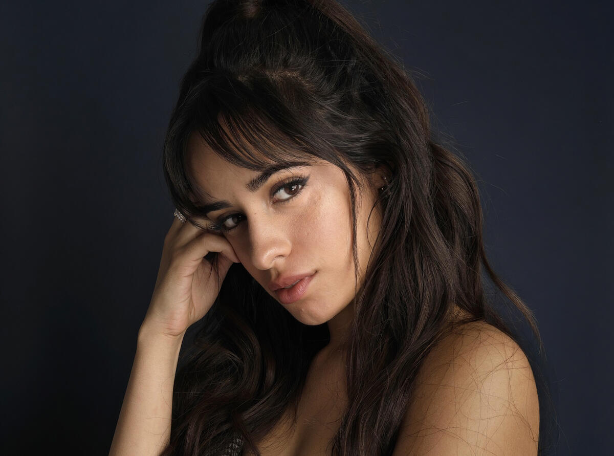Dark-haired Camila Cabello against a dark background