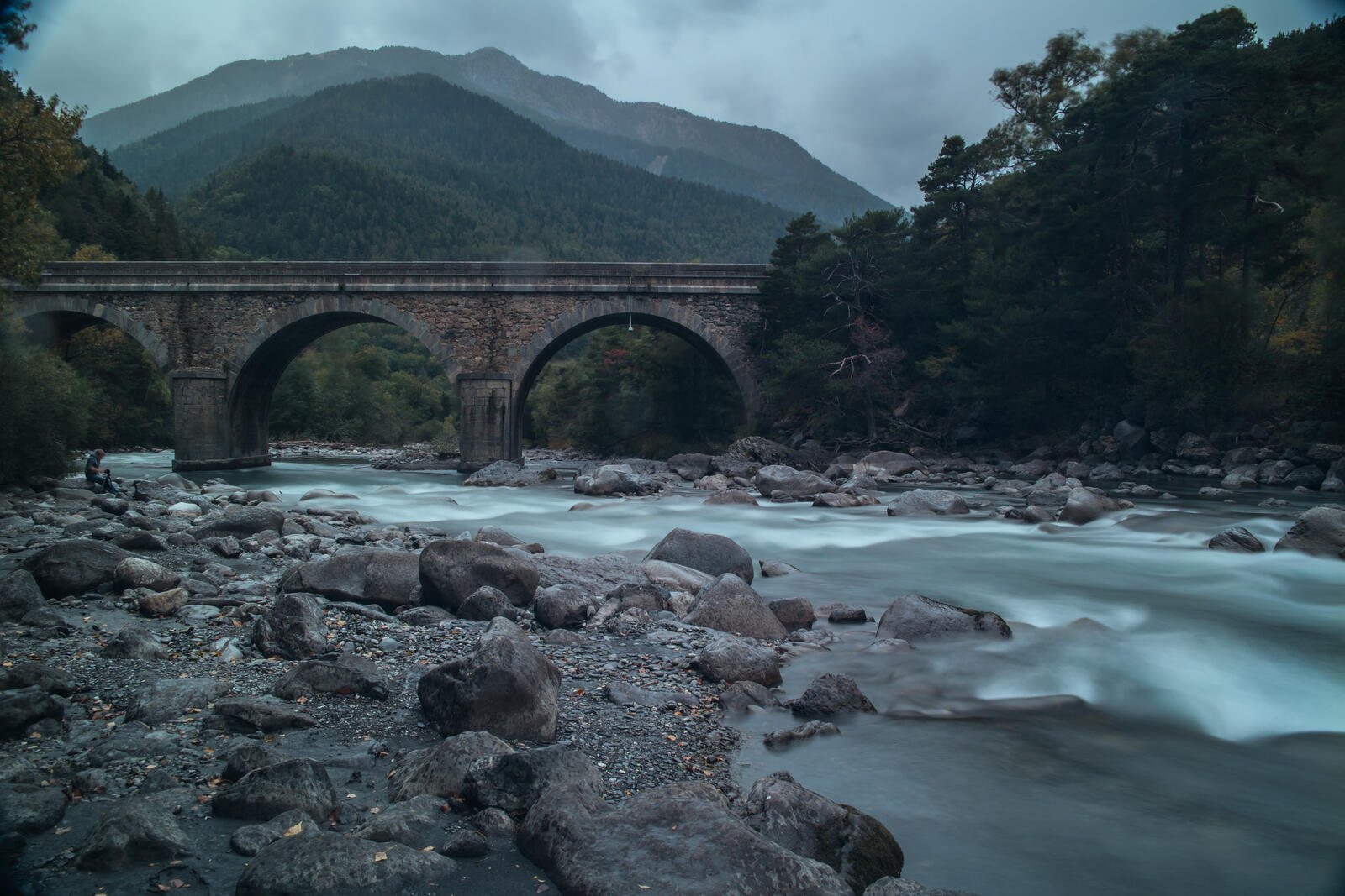 Бесплатное фото Каменный мост через реку с сильным течением в пасмурную погоду