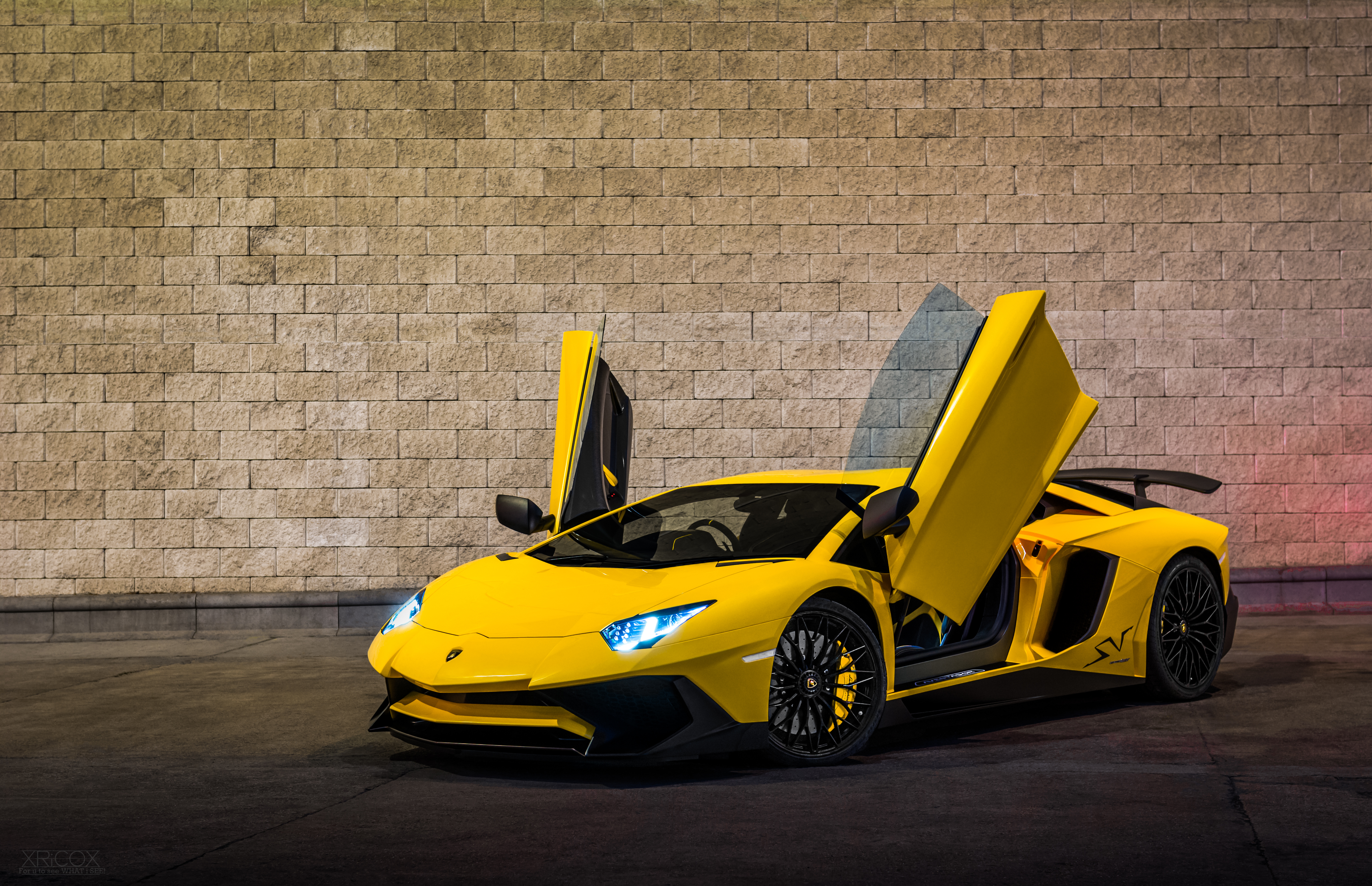A picture of a yellow Lamborghini Aventador with the doors open.