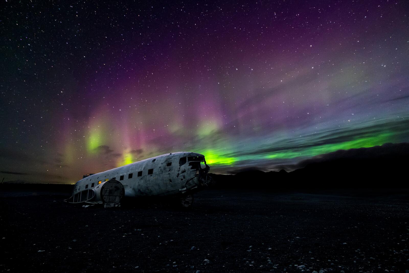免费照片被摧毁的飞机与夜空中的北极光相映成趣