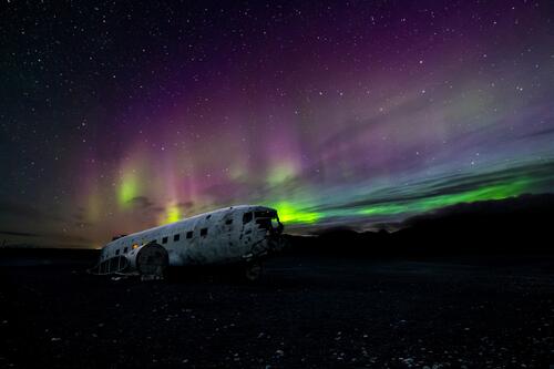 A wrecked airplane against the night sky with northern lights