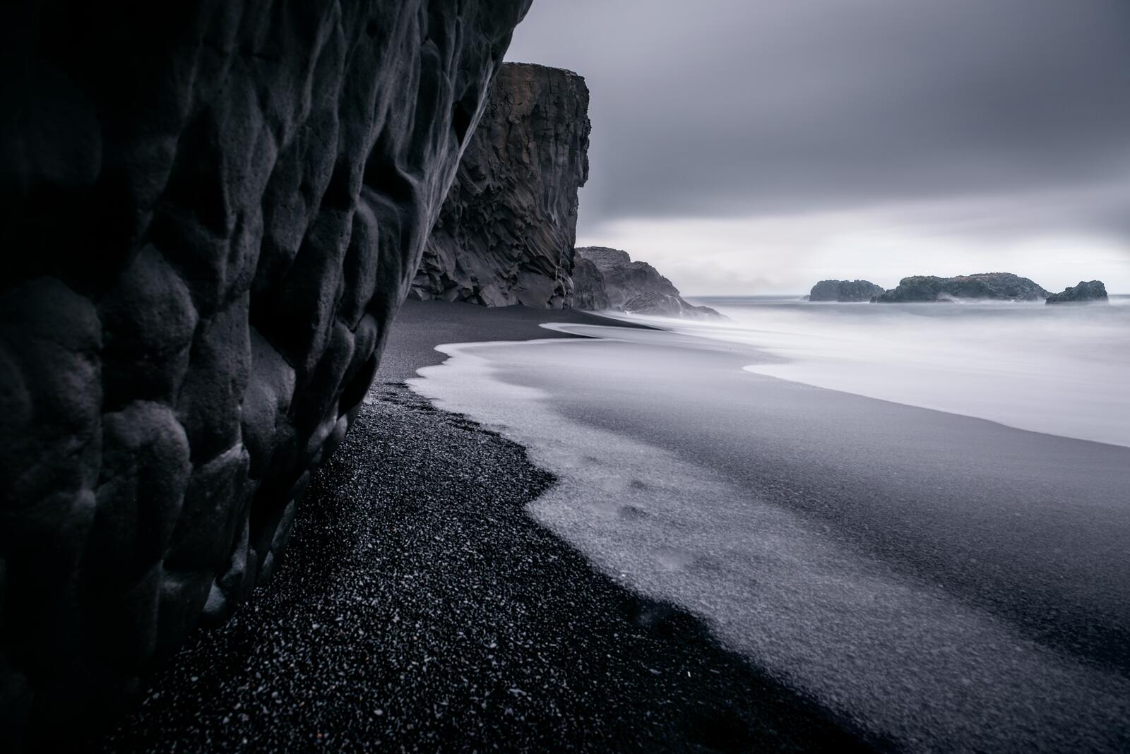 Бесплатное фото Галька на берегу у скалы на монохромном фото