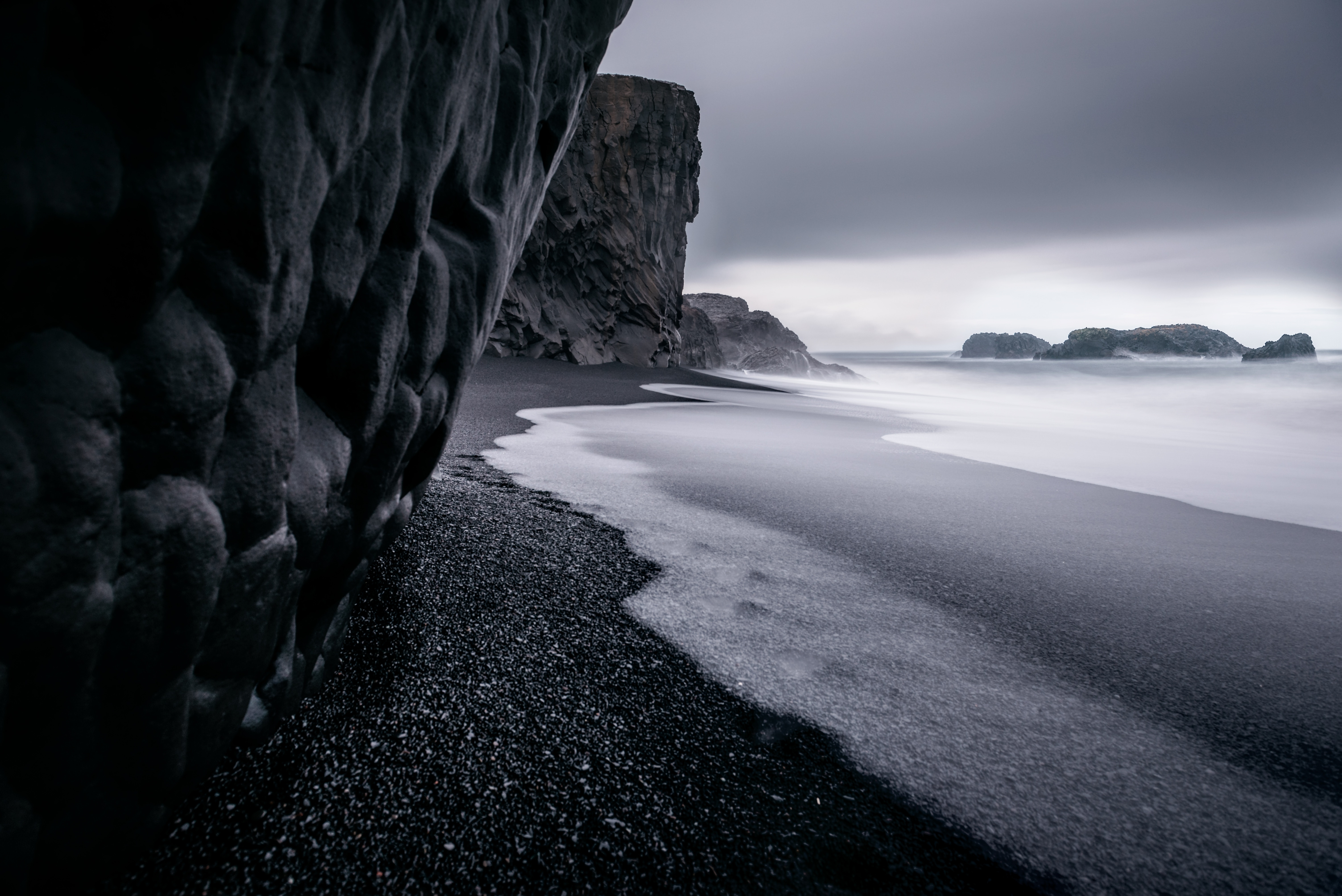 Бесплатное фото Галька на берегу у скалы на монохромном фото