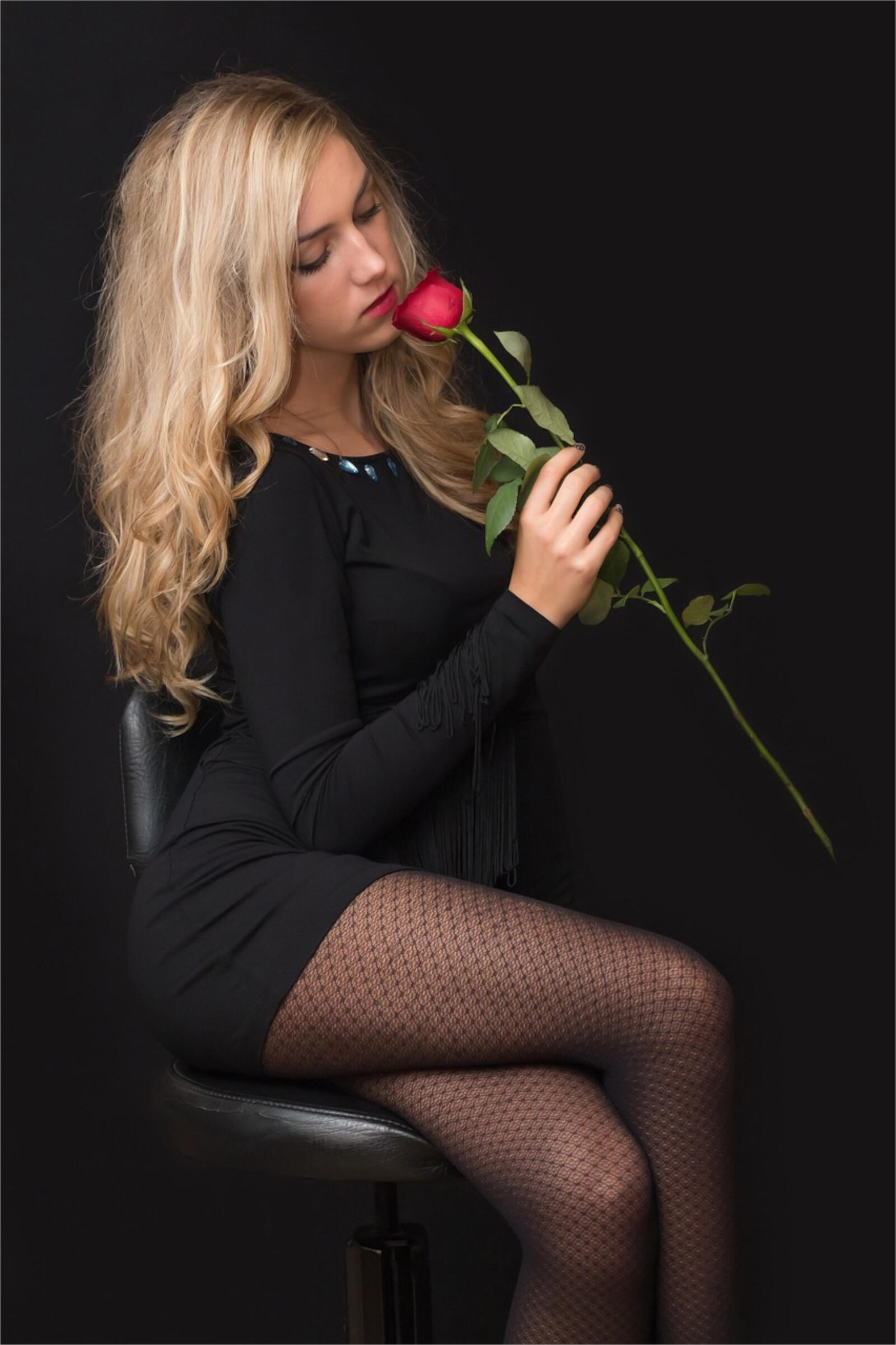 Бесплатное фото Блондинка в черном вечернем платье с красной розой