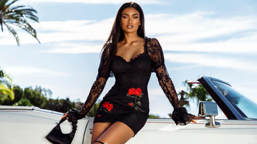 Kelly Gale in a black dress in front of a convertible