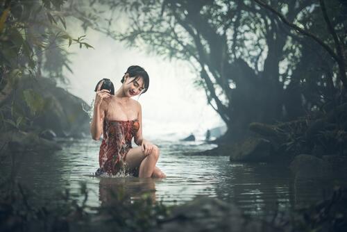 An Asian woman washes in the river