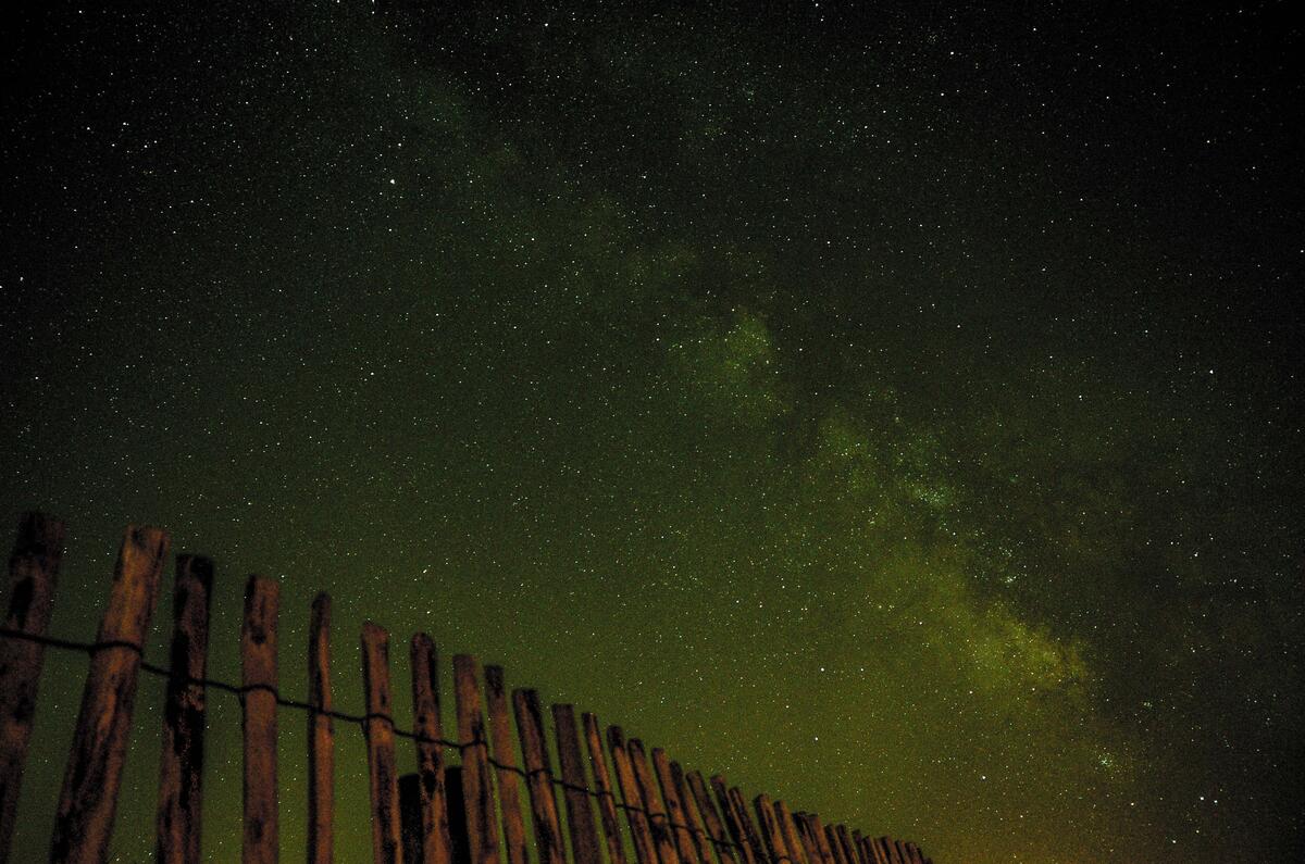 旧木栅栏衬托着黑色的天空和星星