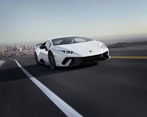 Белая Lamborghini Huracan Performante едет по дороге на высокой скорости