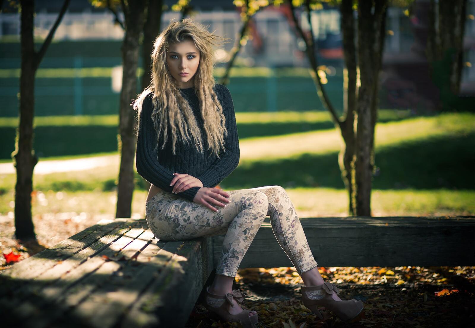 Бесплатное фото Кучерявая девушка сидит на лавочке в парке