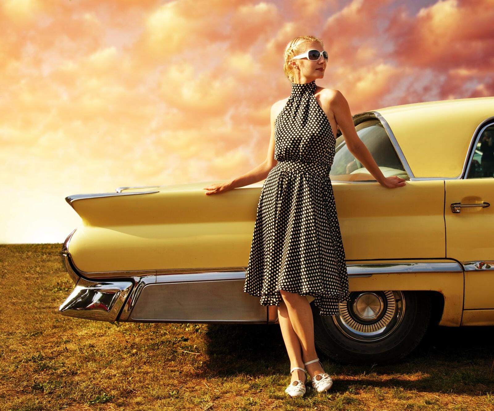 Free photo Girl in a polka-dot dress in front of a retro car