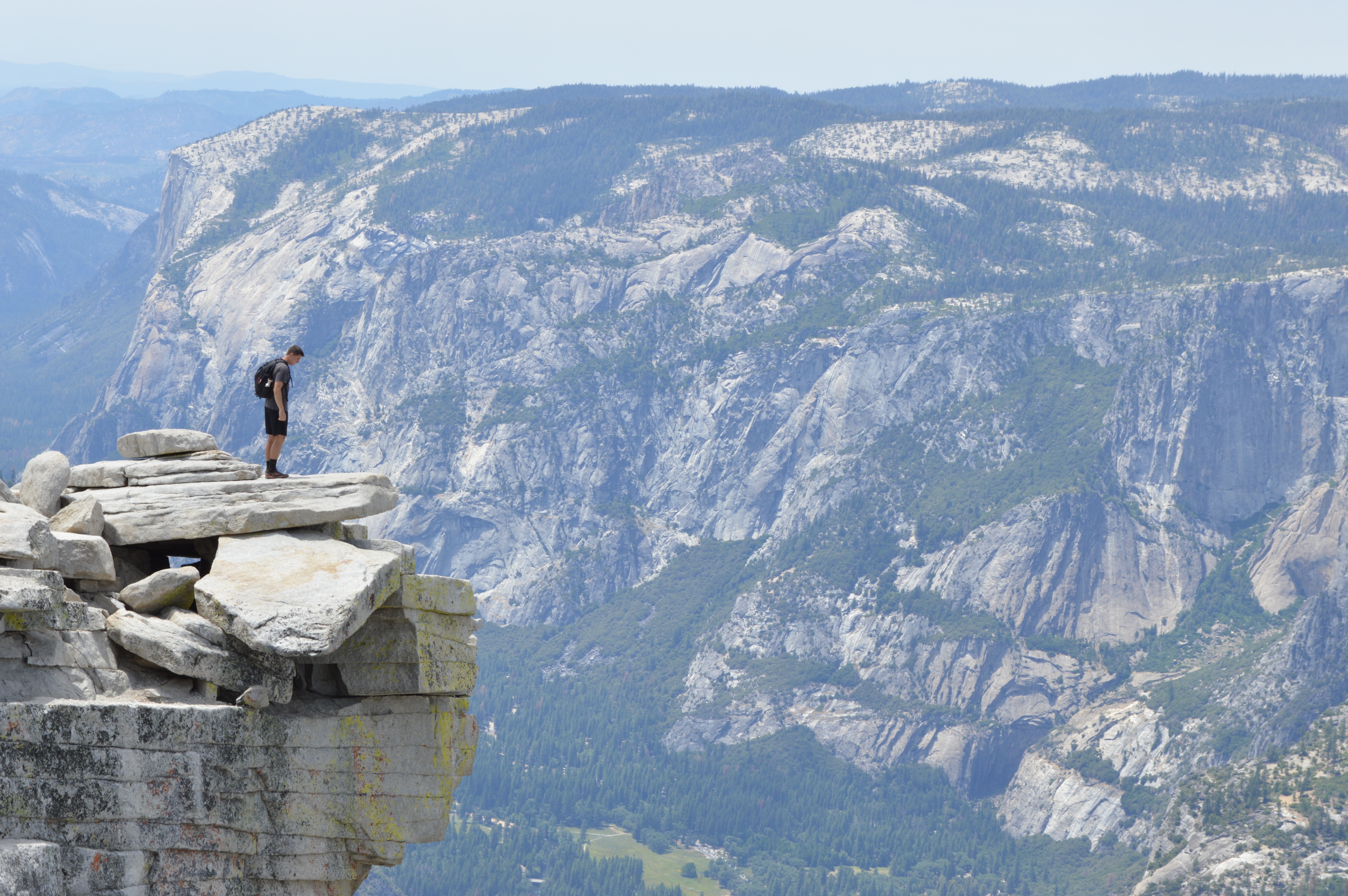 免费照片一个男性旅行者站在悬崖峭壁上，往下看