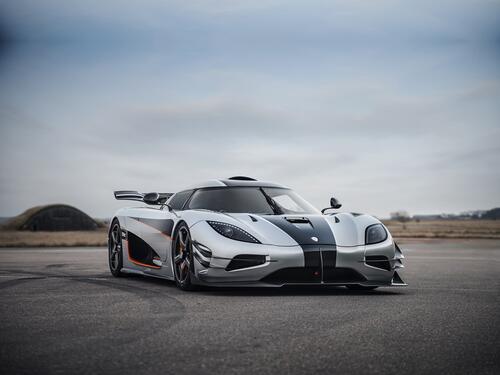 A gray koenigsegg agera with a black stripe on the hood