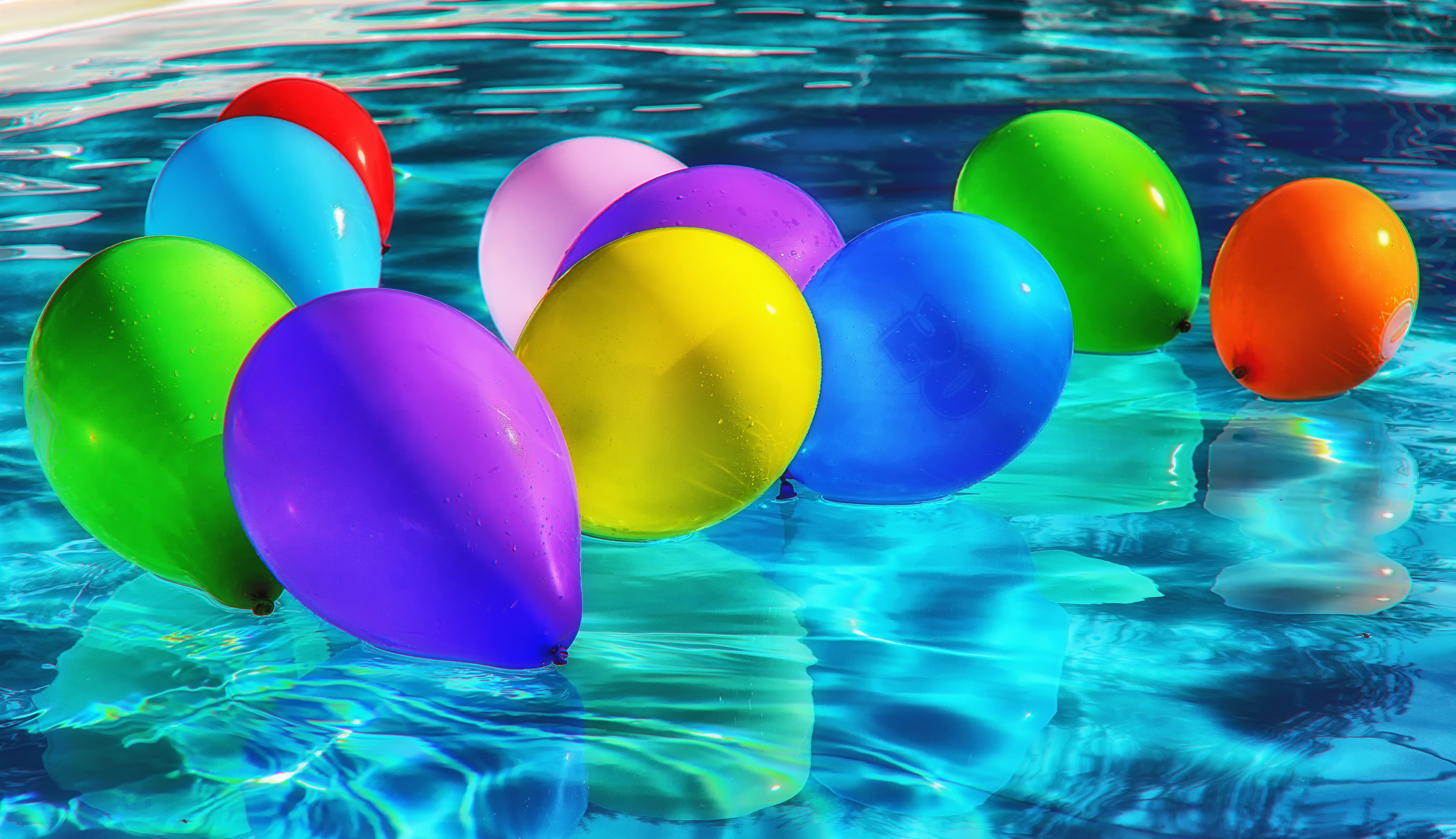 Free photo Multicolored balloons float in the pool