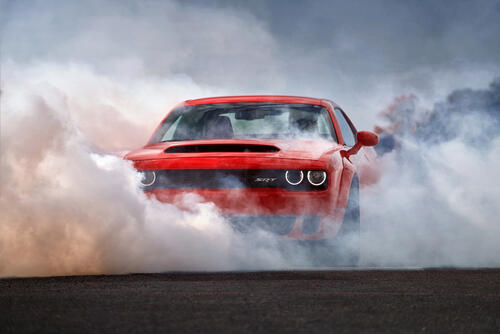 Red Dodge Challenger in thick smoke.