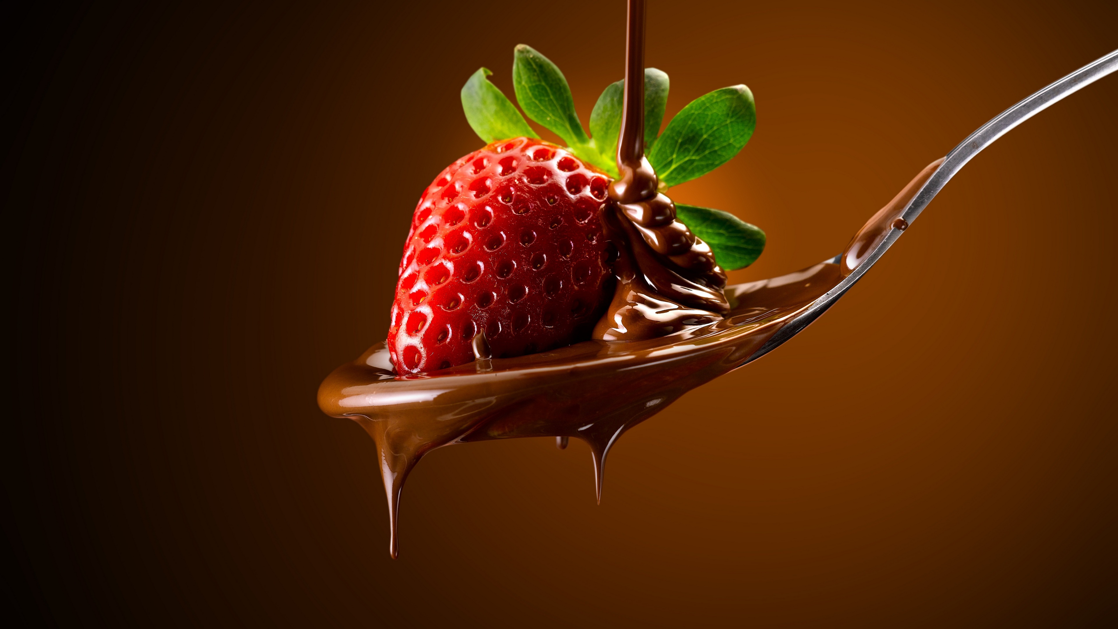 免费照片用勺子舀上裹有液态巧克力的草莓