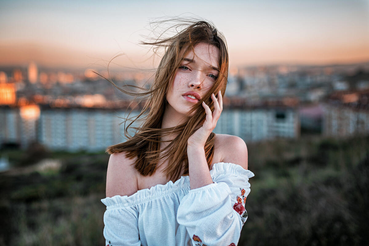 A girl with exposed shoulders on a windy day.