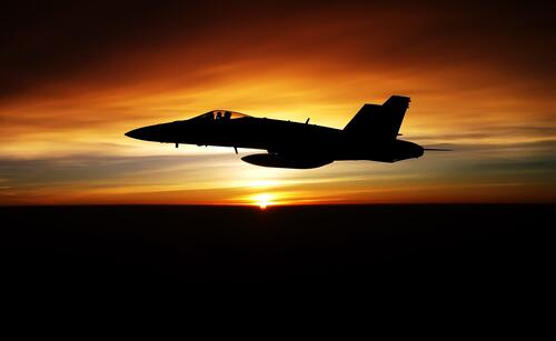 Silhouette of a fighter plane at sunset