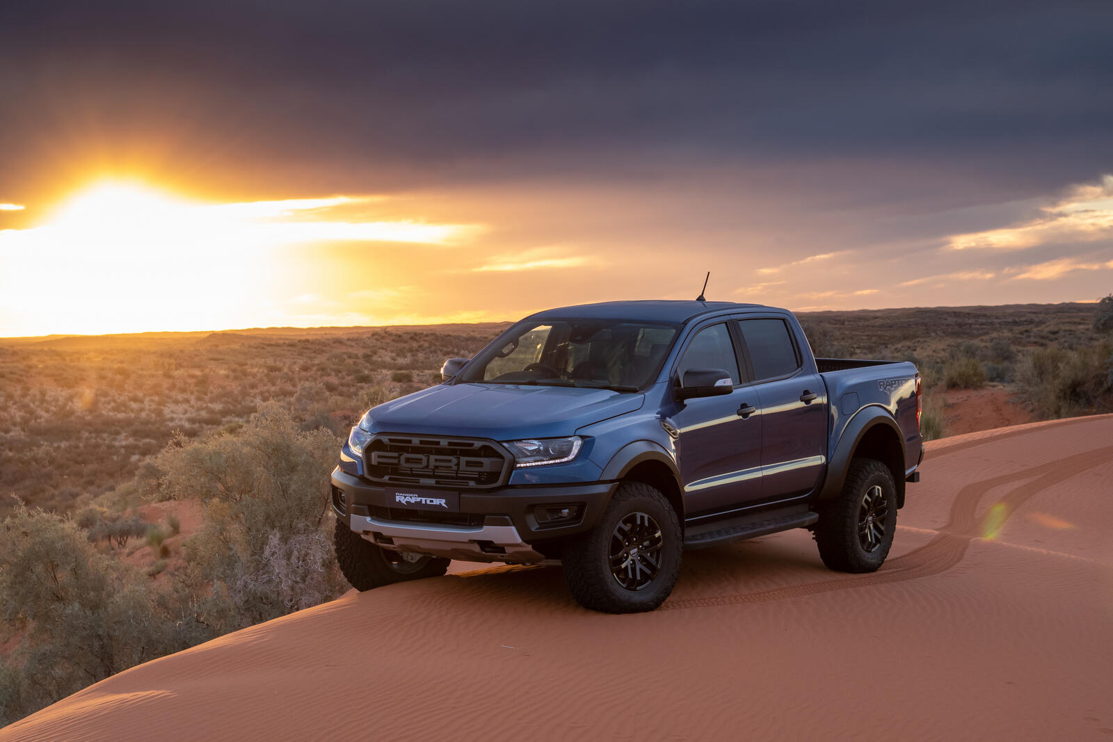 Free photo The 2019 Ford Ranger Raptor in blue drives over sand dunes
