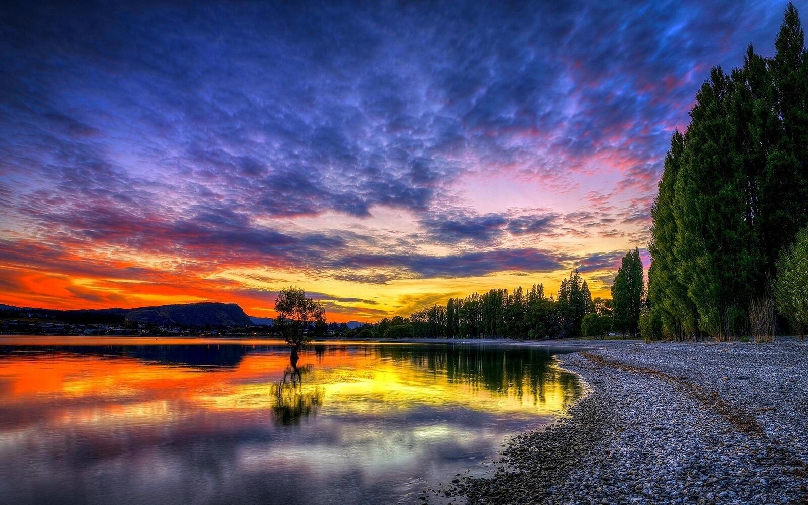 Бесплатное фото Яркий закат на берегу озера с галькой