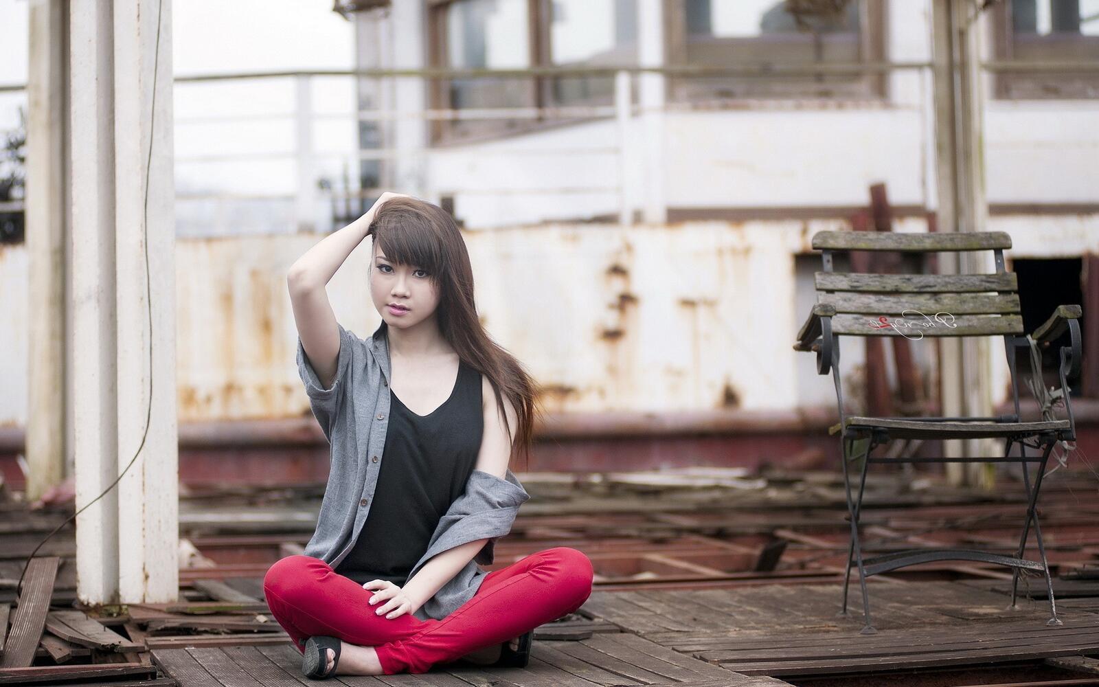 Free photo An Asian-looking brunette sits on a wooden floor