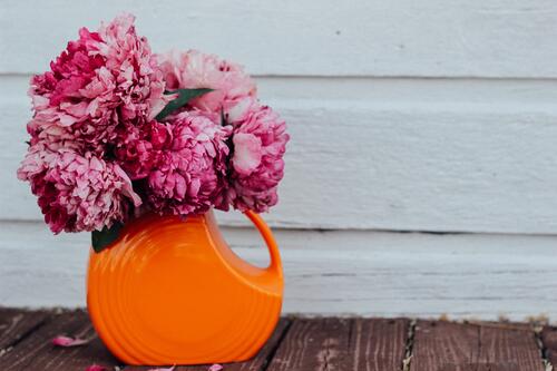 Розовые цветы в оранжевой вазе