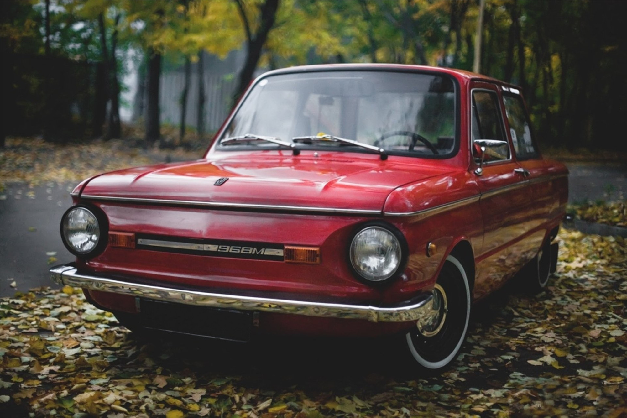 Красный  ЗАЗ-968М стоит на опавших листьях