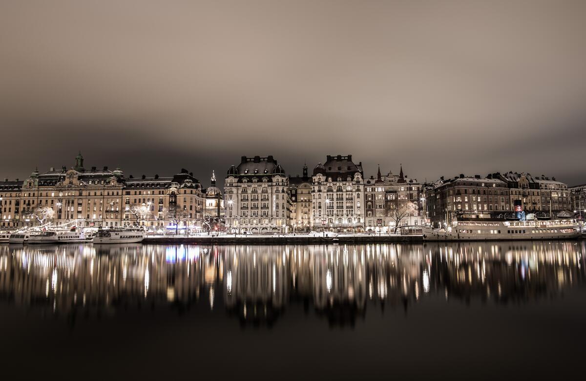 Night houses by the water are reflected in a river in Switzerland