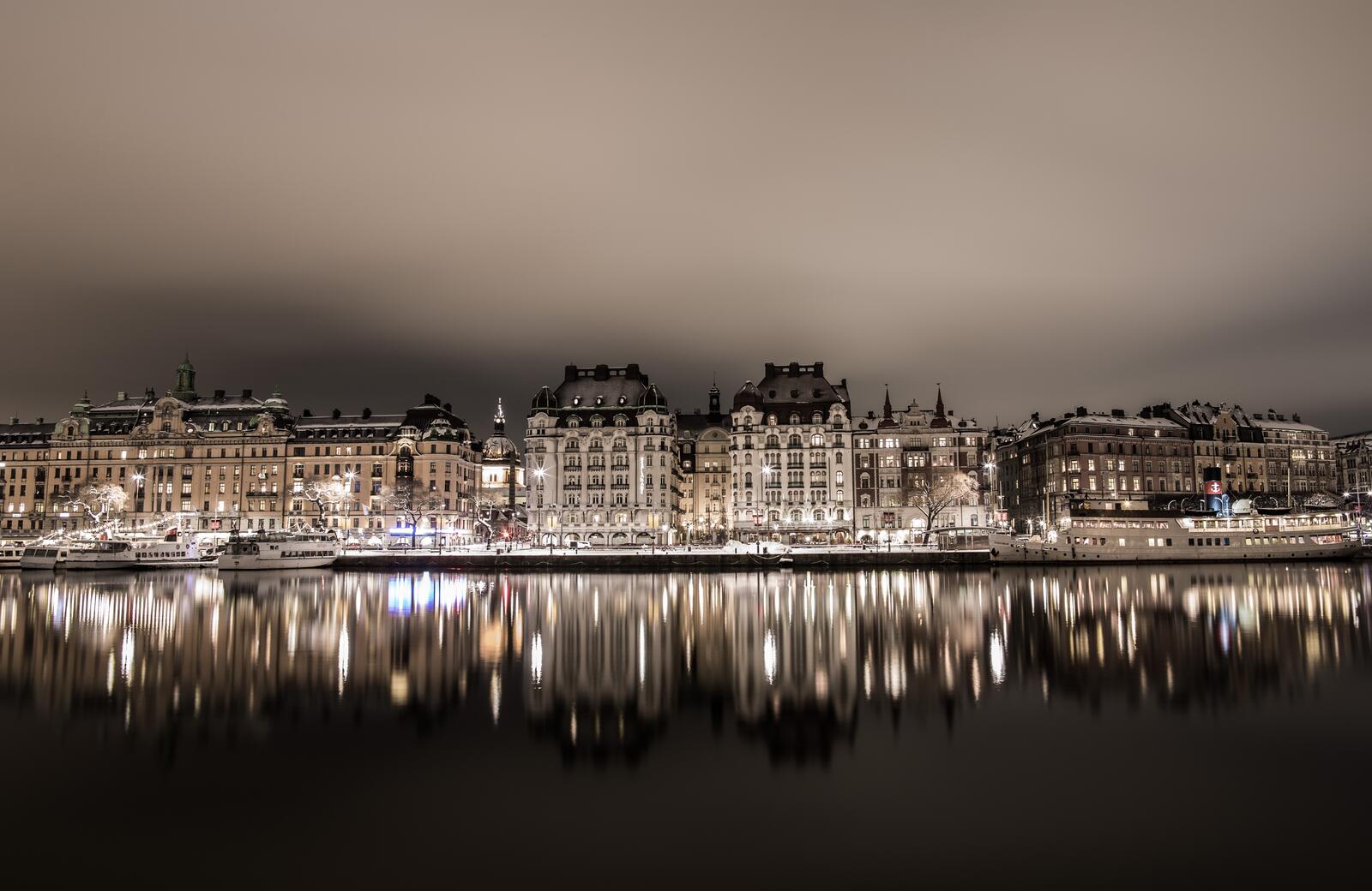 Free photo Night houses by the water are reflected in a river in Switzerland