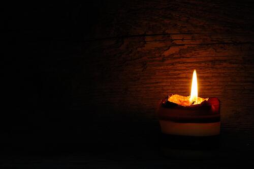A lone candle burns in the darkness