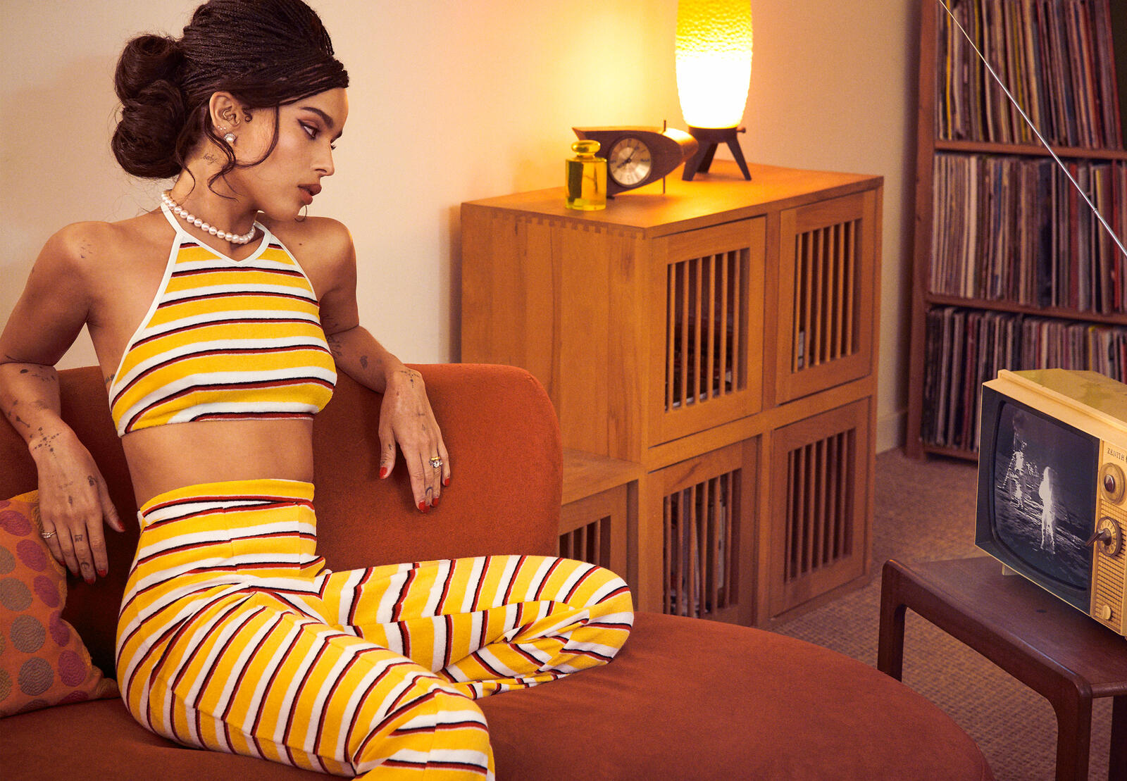 Бесплатное фото Зои Кравиц сидит на диване в желто-белой летней одежде