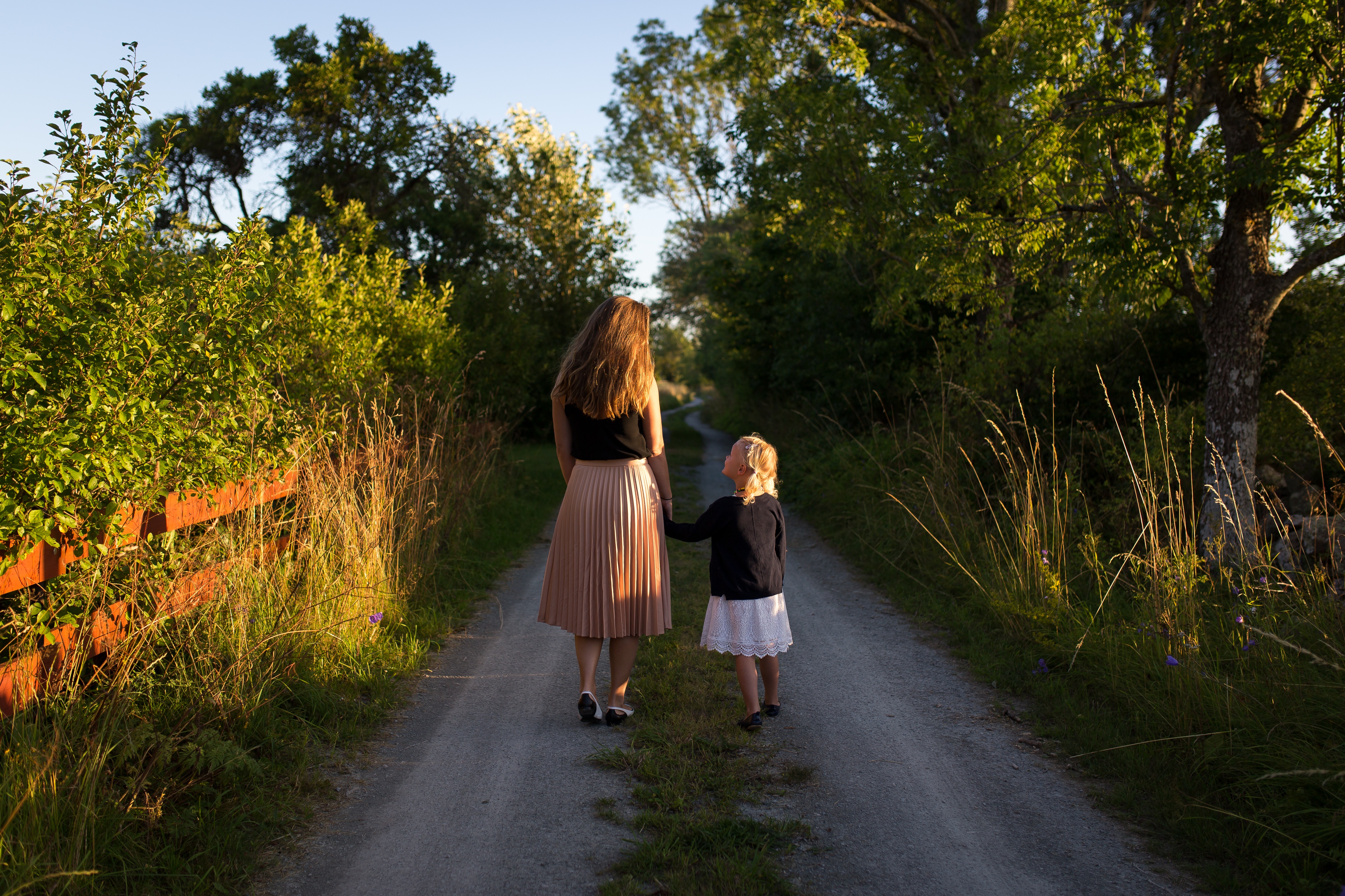 Free photo Mom and daughter walking down a country road