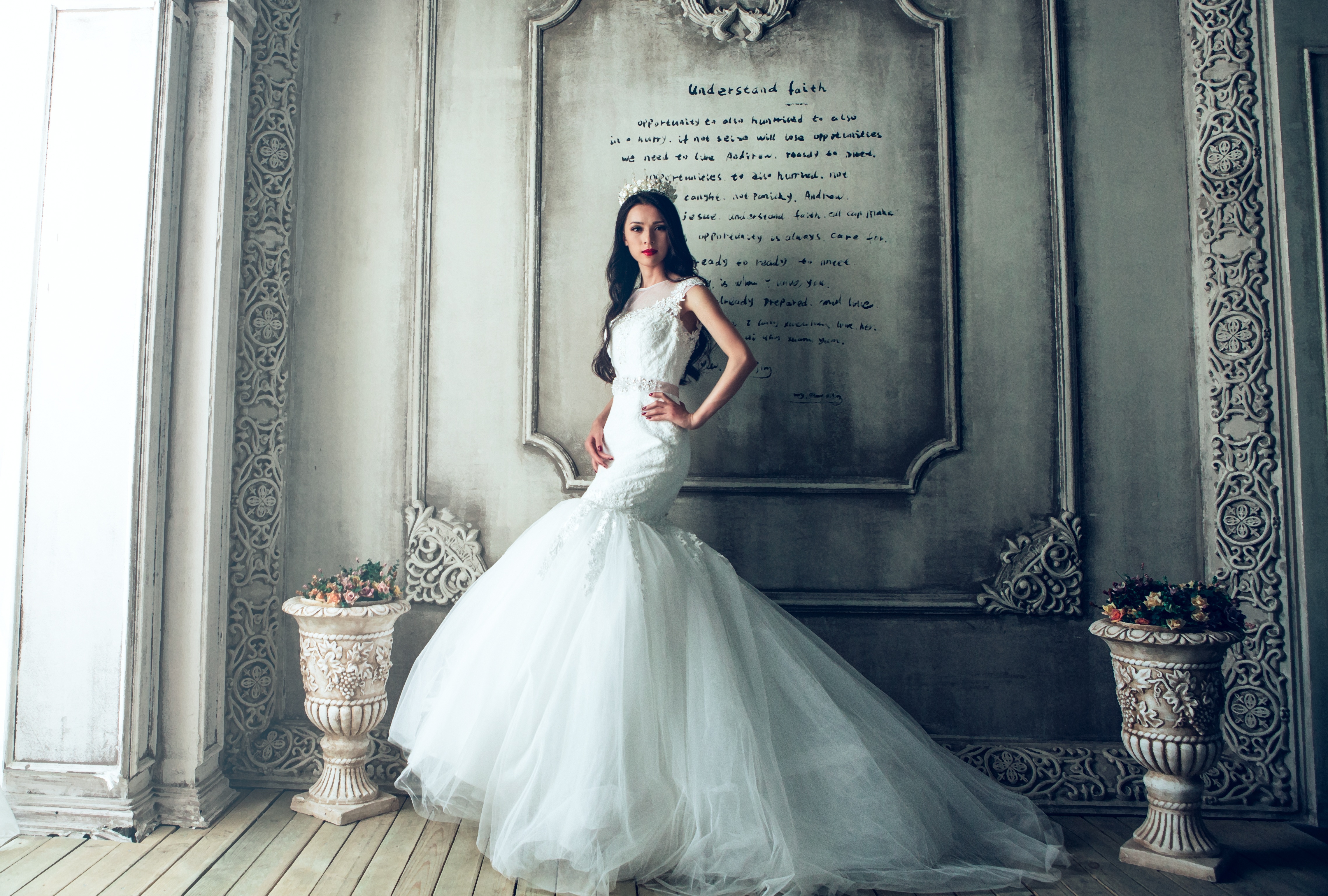 A girl in a wedding dress poses in a gloomy room