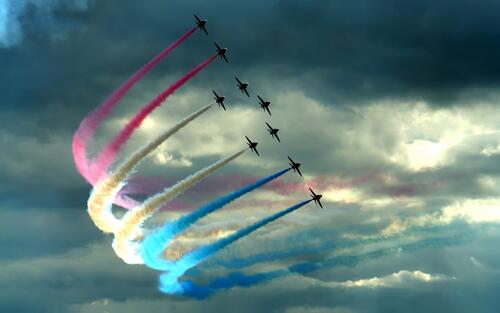 A parade of airplanes with colored smoke