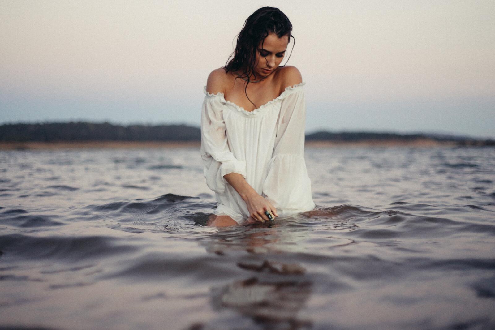Free photo A girl in a white nightie walks into a river