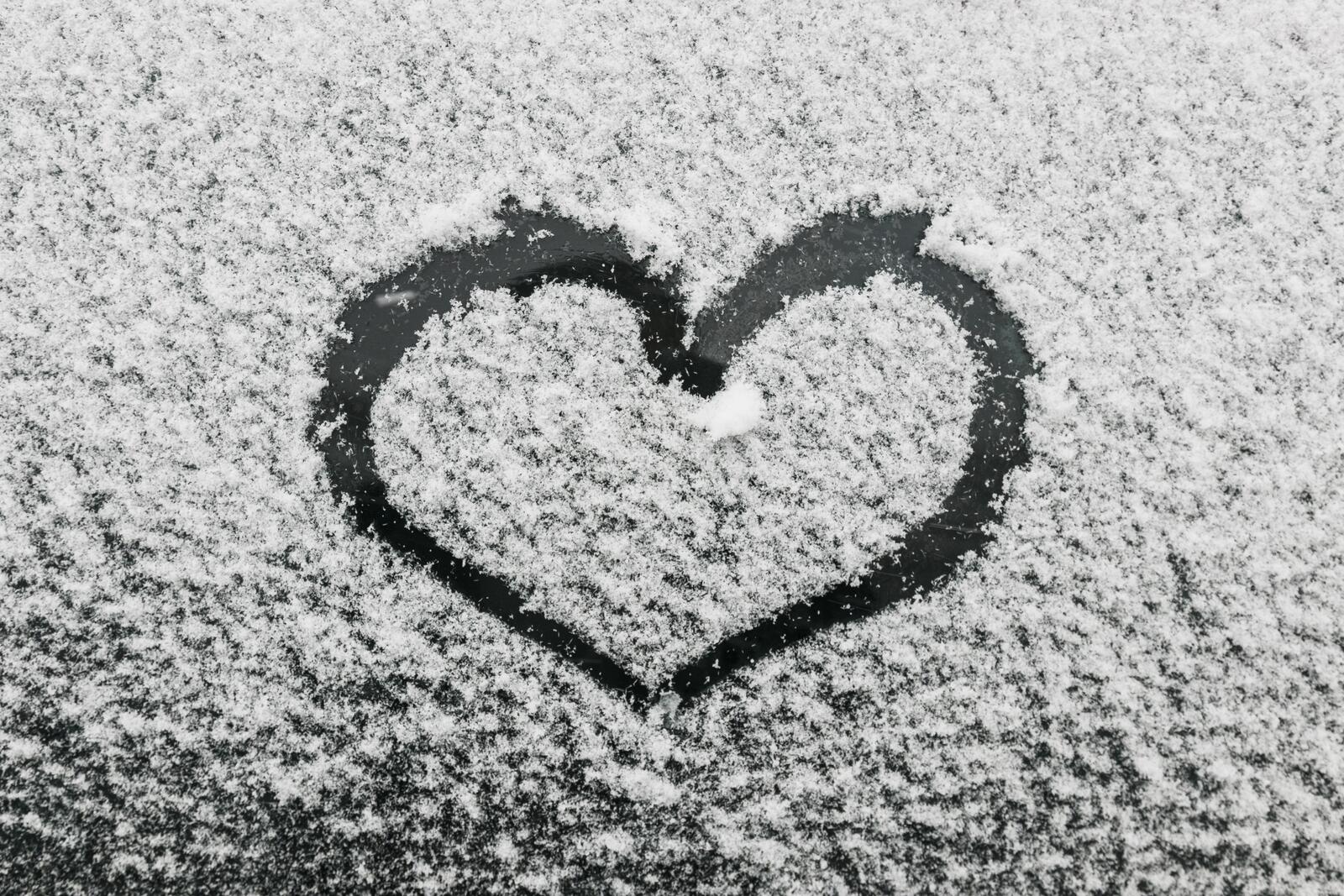 Free photo Drawing a heart out of snow on the shore of a frozen lake