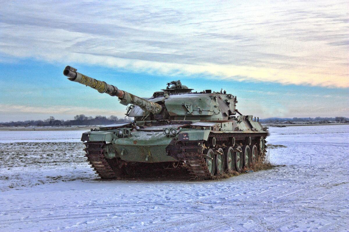 A tank rides through a snowy field