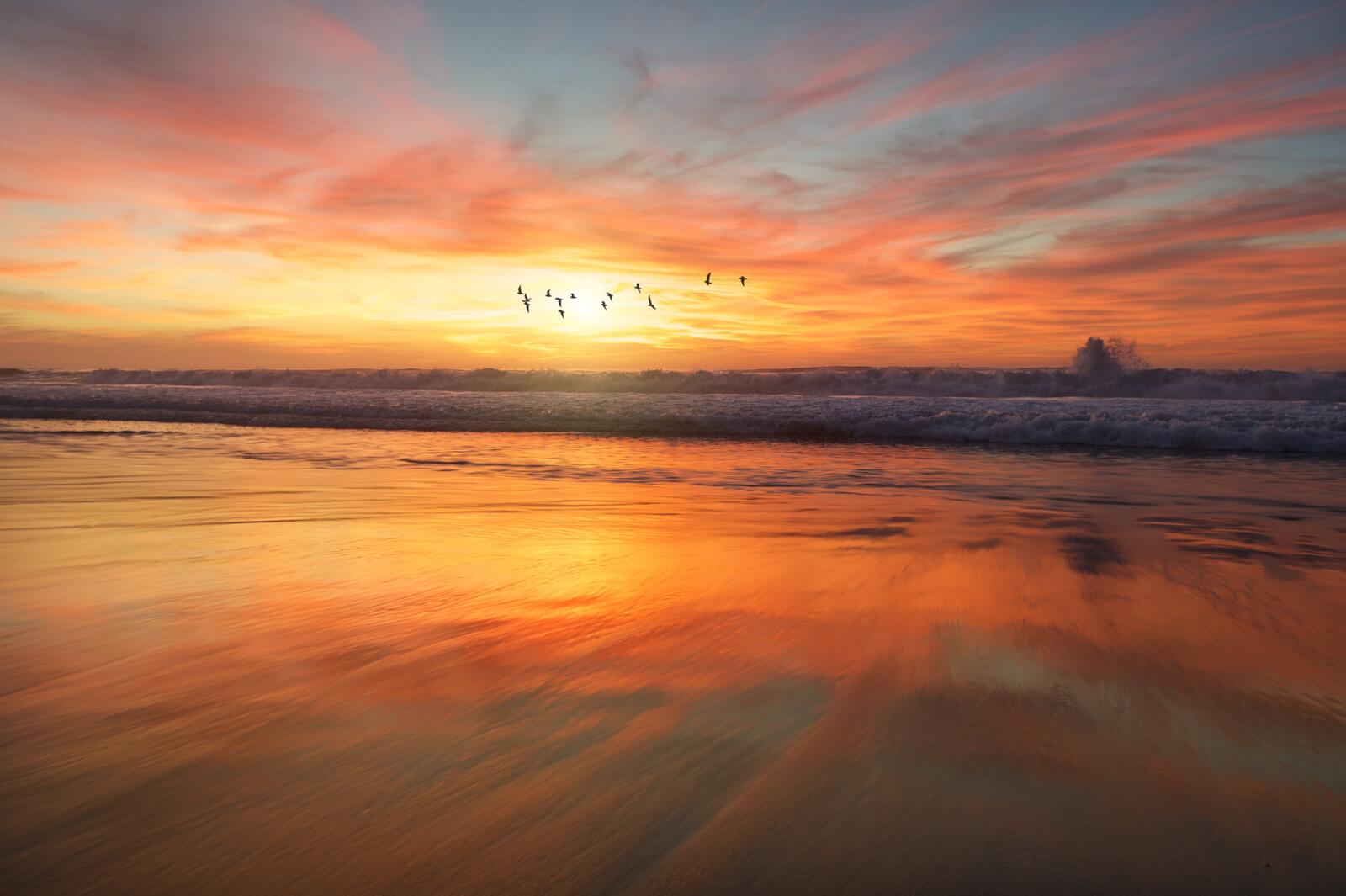 Бесплатное фото Волны разбиваются о песочный пляж на закате дня
