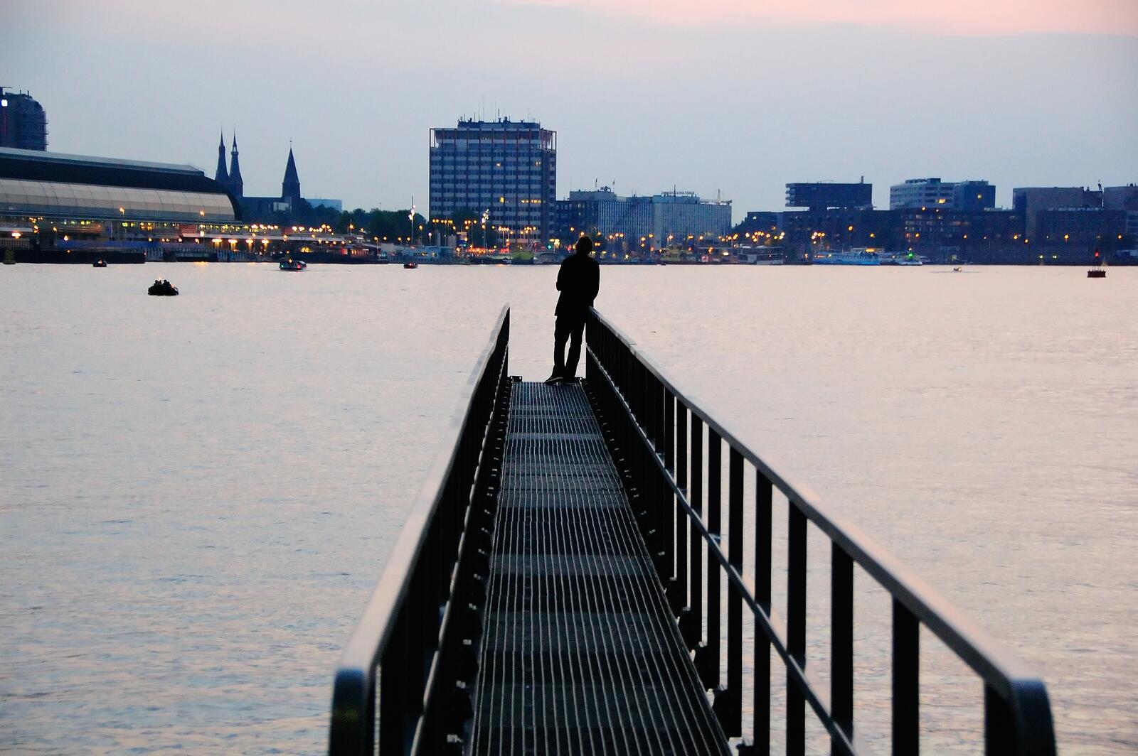 Бесплатное фото Мужчина стоит на краю пирса с видом на город