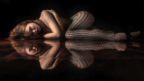 A girl lies on a mirrored floor in the darkness