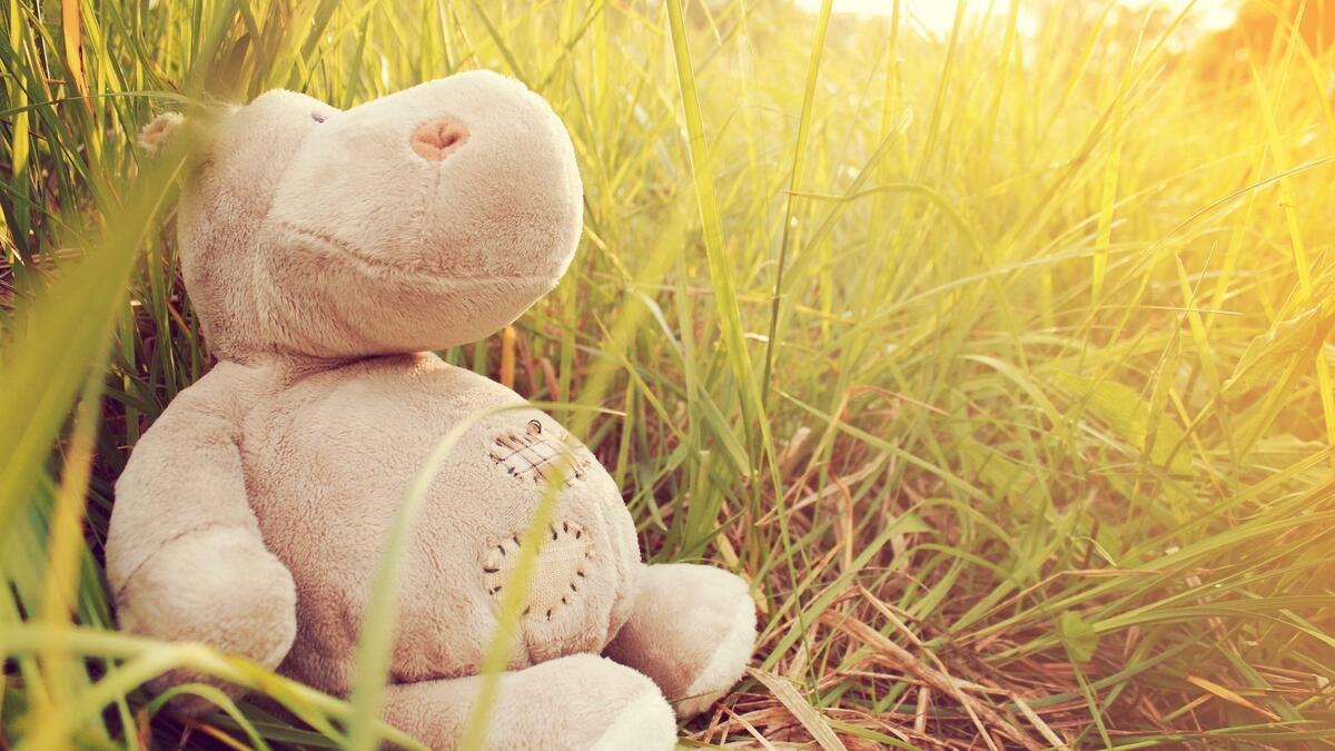 Мягкая игрушка бегемот лежит на зеленой траве