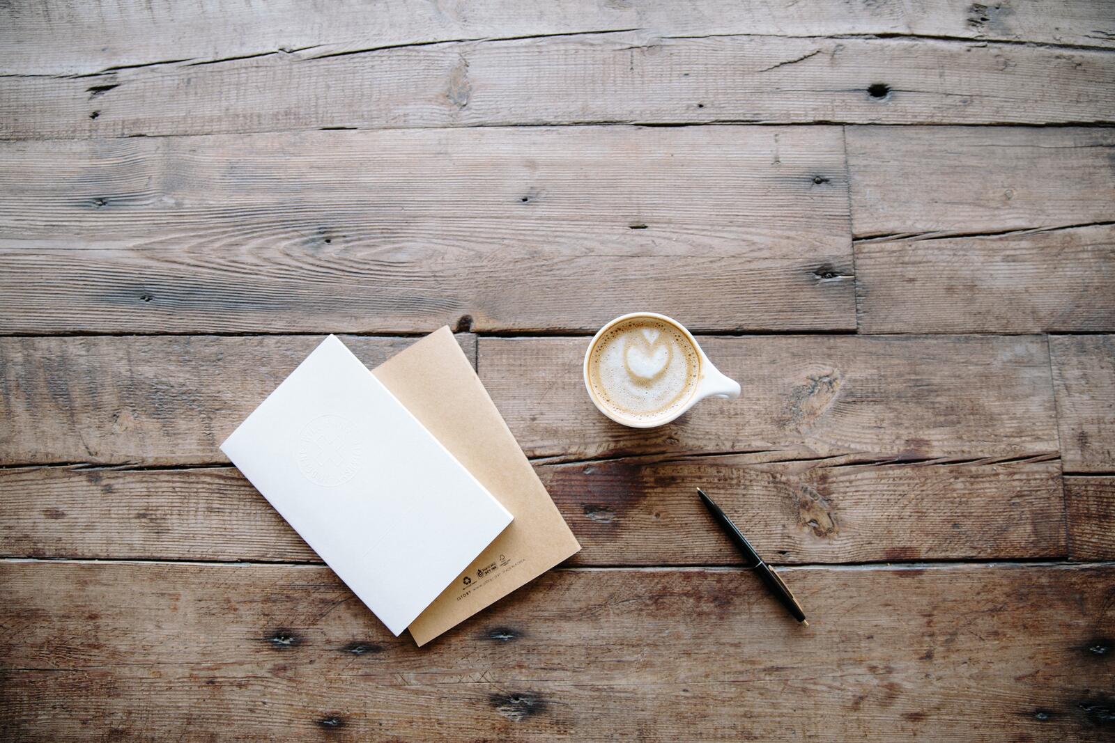 Free photo Diary with a cup of coffee on a wooden background