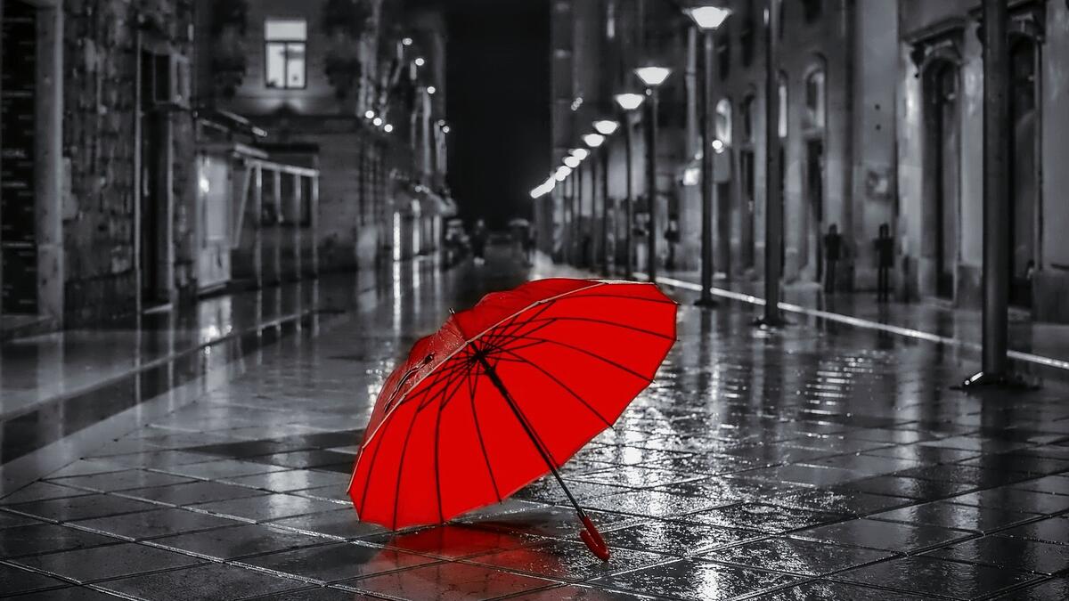 一把打开的红伞躺在夜晚的城市街道上