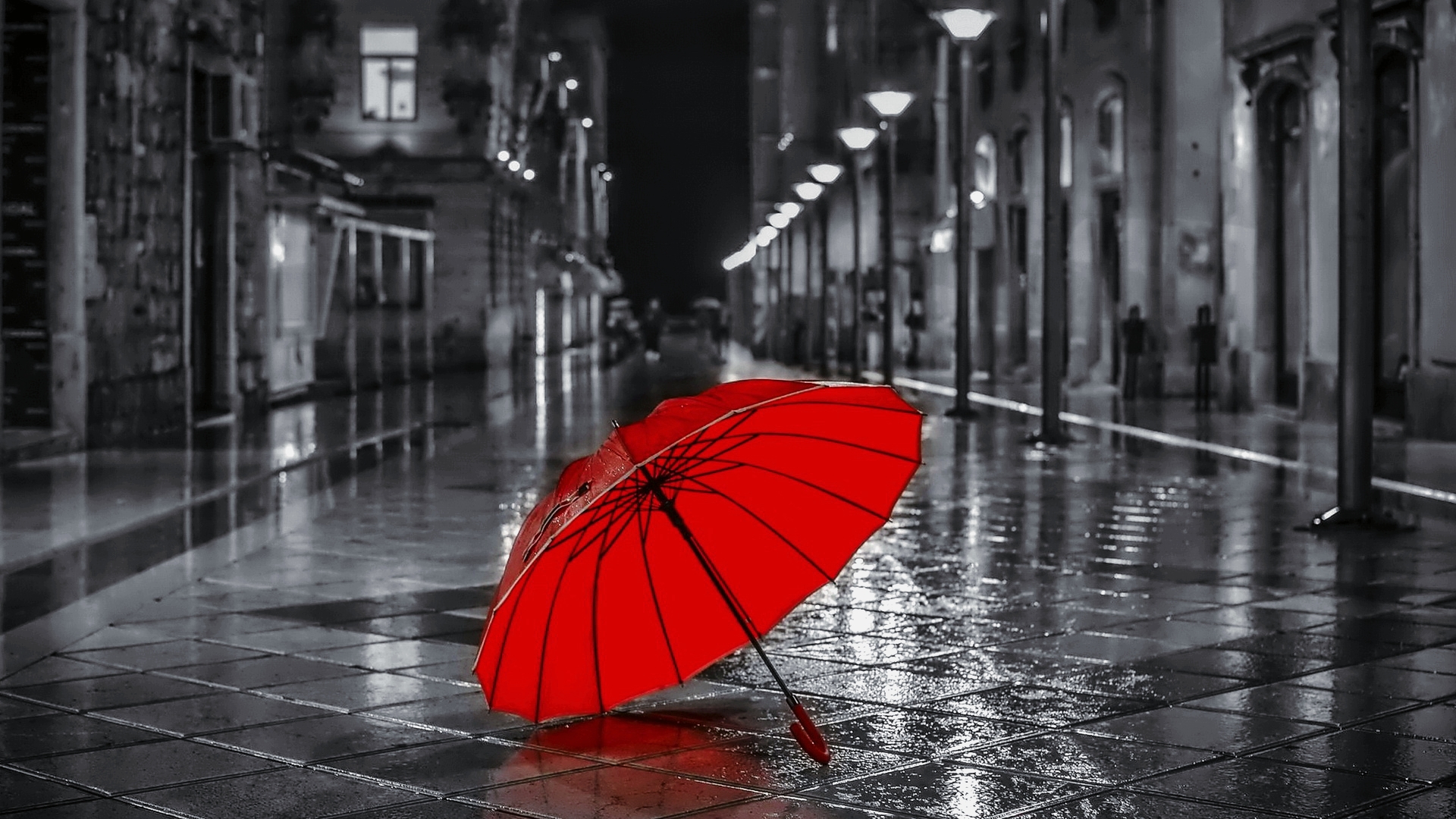 Раскрытый красный зонт лежит на улице ночного города