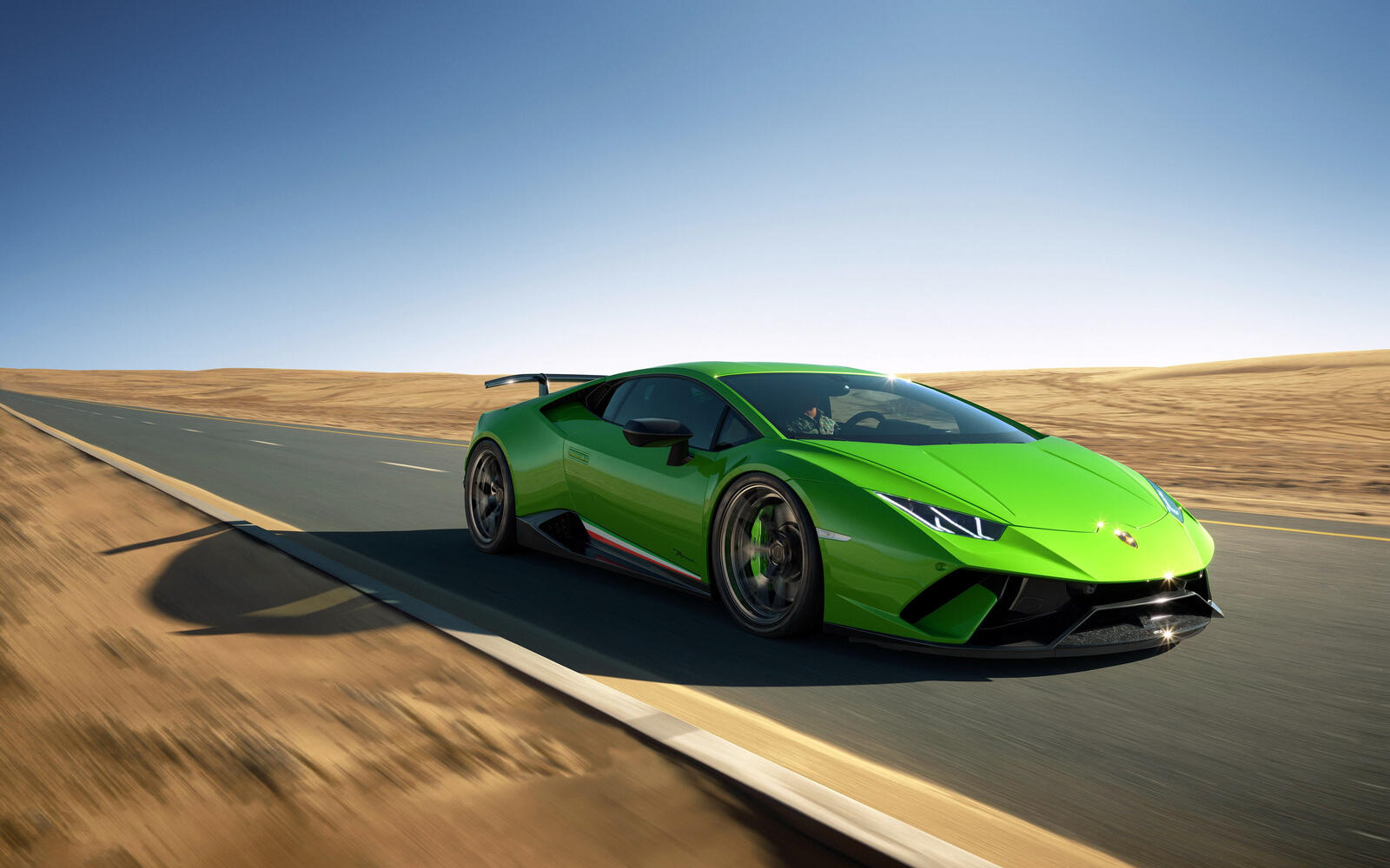 Бесплатное фото Ярко-зеленый Lamborghini Huracan едет по дороге в пустыне