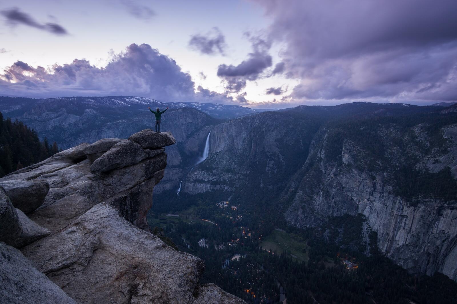 Free photo A man stands at the rim of a mountain with his arms outstretched