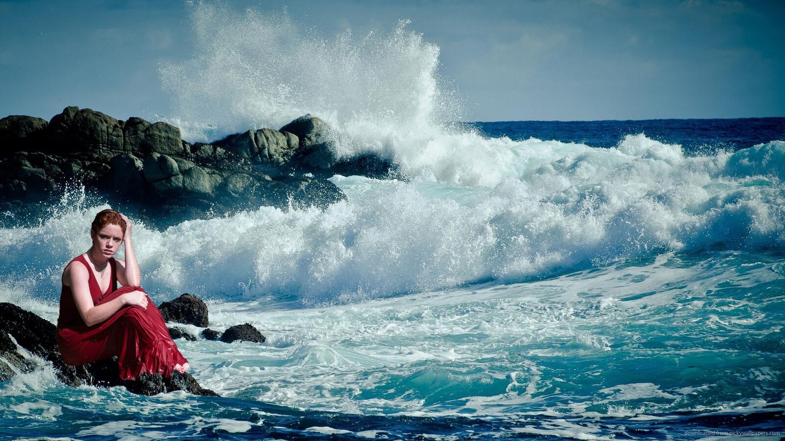 Бесплатное фото Девушка сидит грустить на берегу моря рядом с волнами