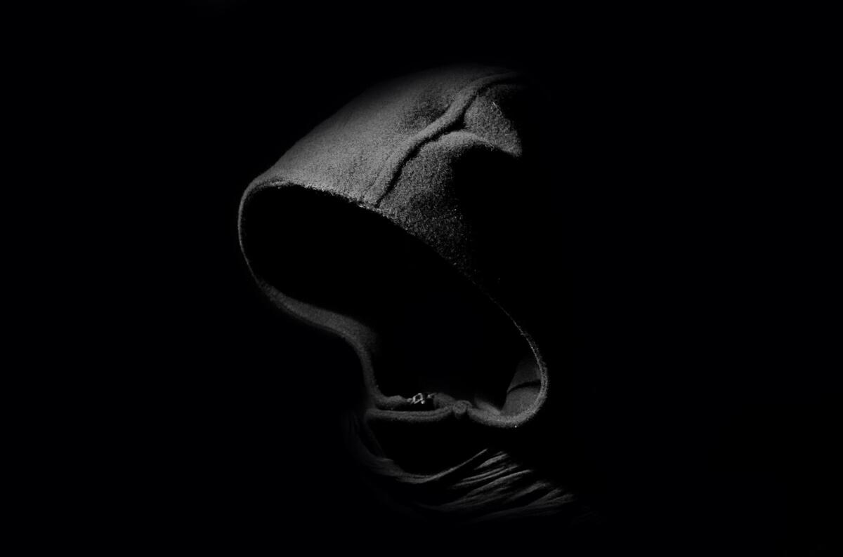 A hooded silhouette in the dark.