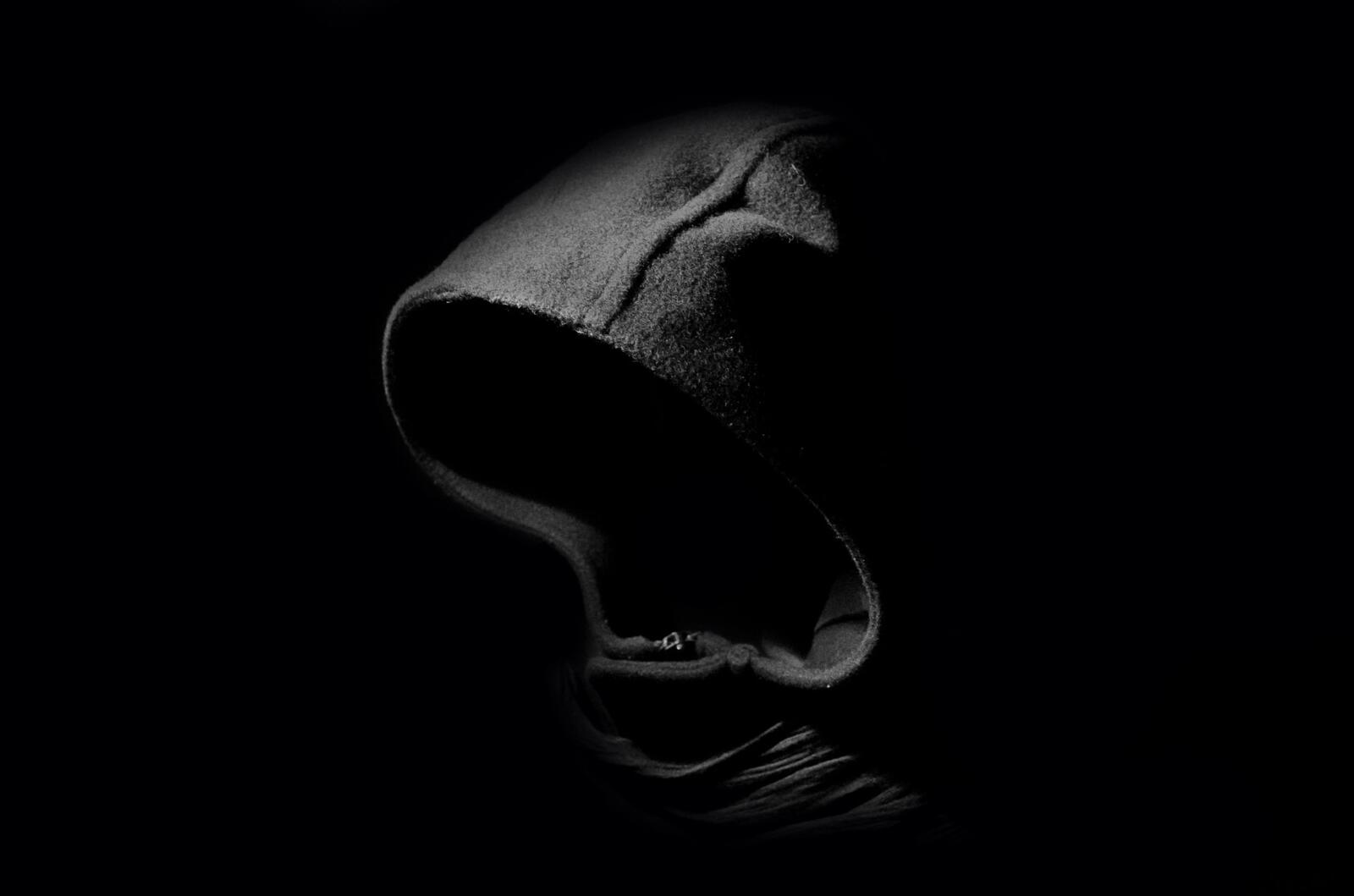 免费照片黑暗中一个戴着头罩的人影。